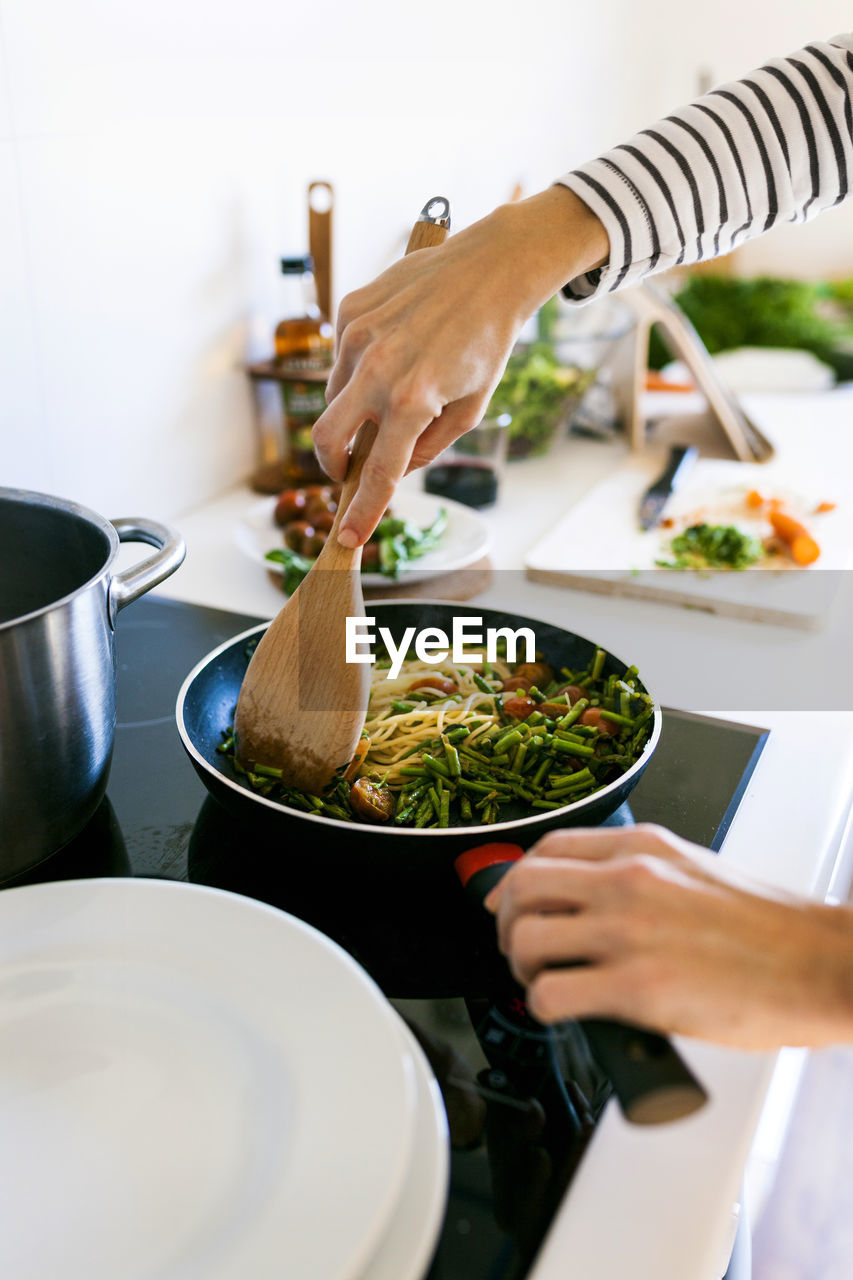 Young woman cooking vegan pasta in her kitchen