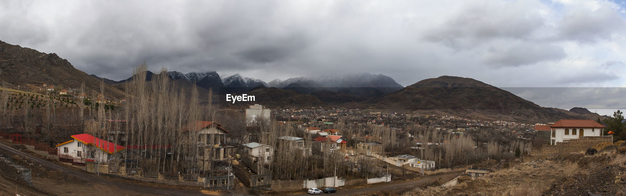 PANORAMIC SHOT OF BUILDINGS AND MOUNTAINS AGAINST SKY