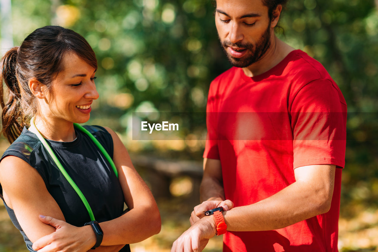 Young couple checking progress on their smart watches after outdoor training