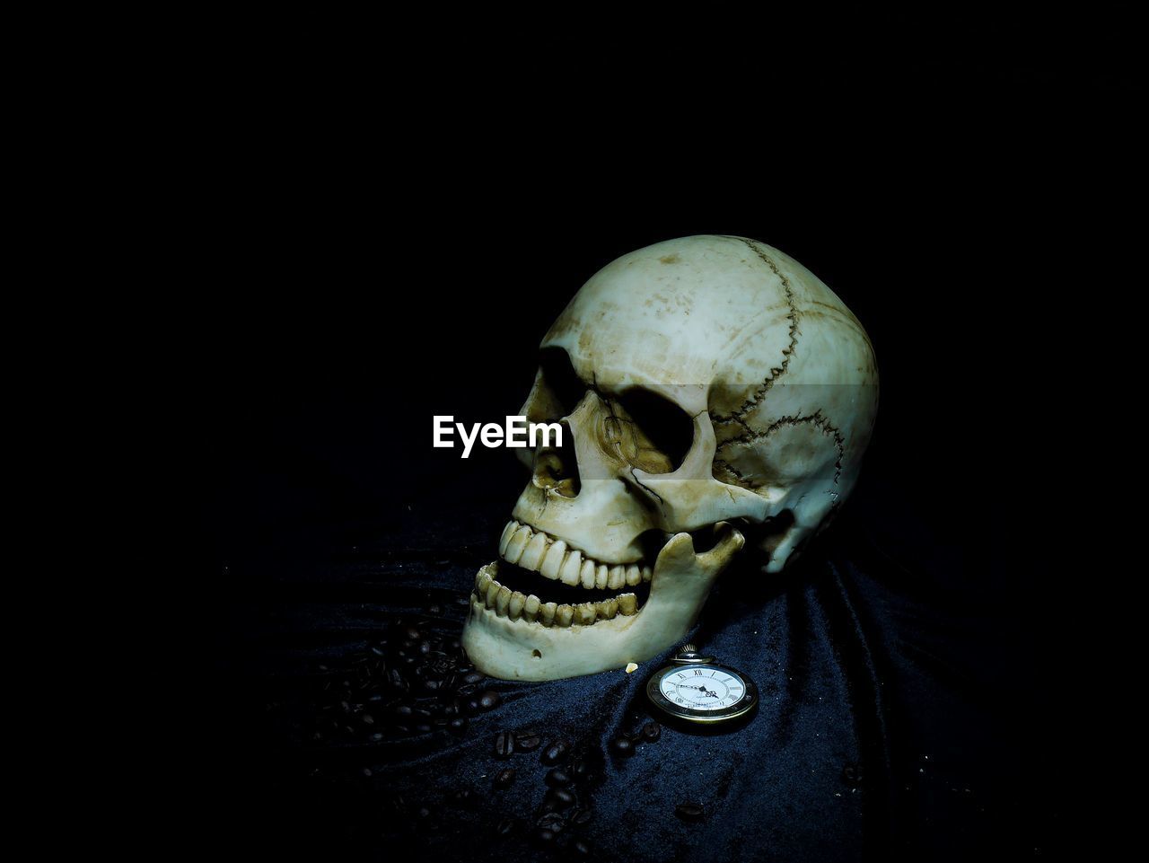 Close-up of human skull and pocket watch on table