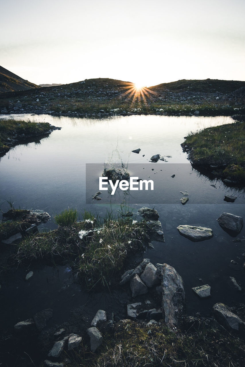 SCENIC VIEW OF LAKE BY ROCKS AGAINST SKY