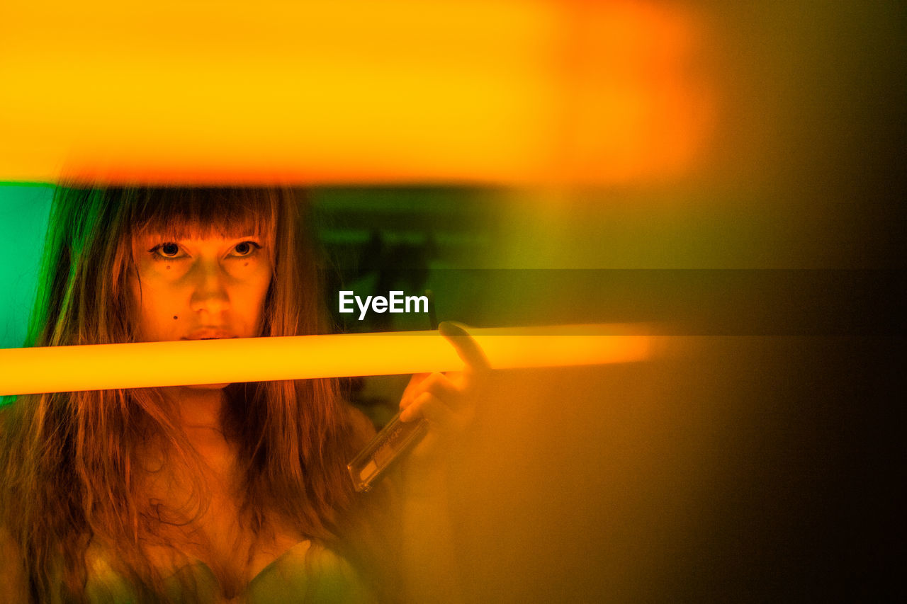 Woman holding illuminated fluorescent light at home