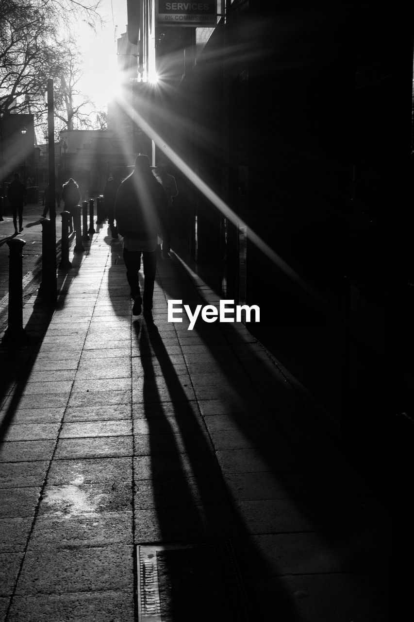 SILHOUETTE OF MAN WALKING ON COBBLESTONE STREET