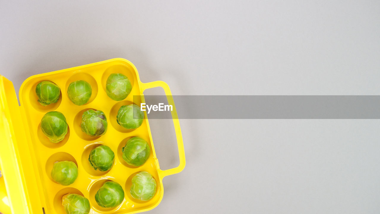 High angle view of raw organic brussel sprouts in yellow pack on grey background