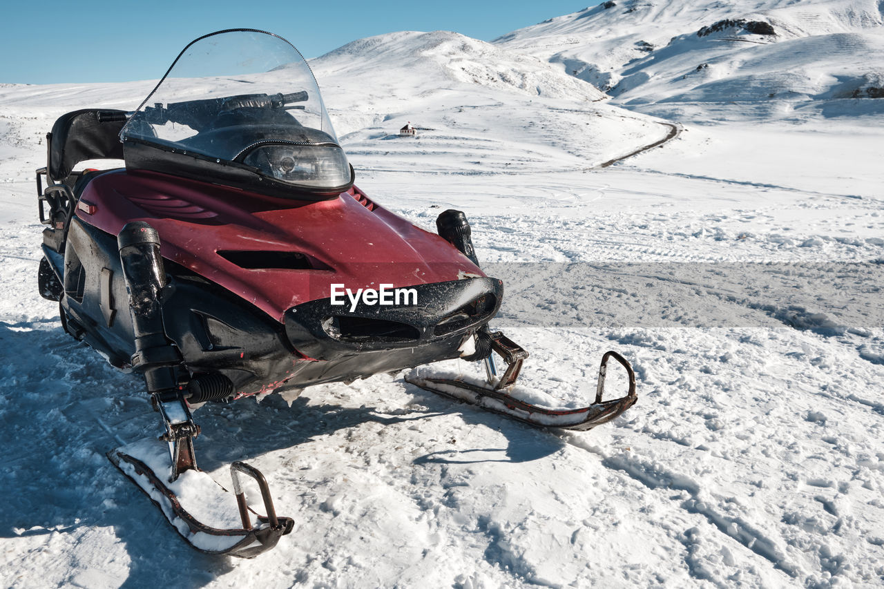 Snowmobile against snow covered slope at background. snow vehicle