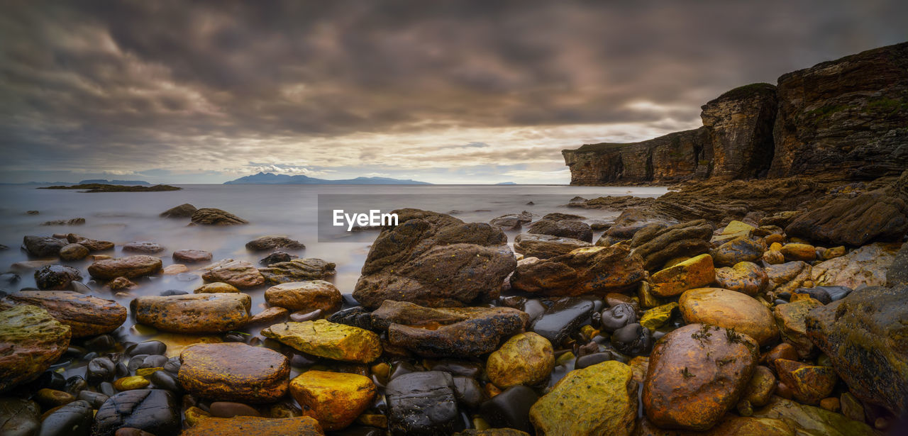 Rocks on beach against sky during sunset