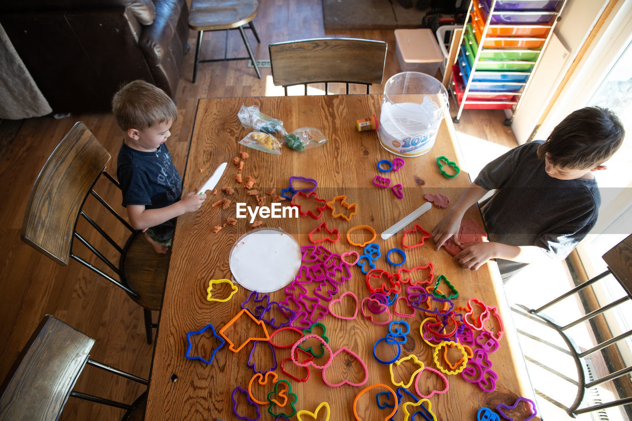 Overhead view of siblings paying with clay and cookie cutters