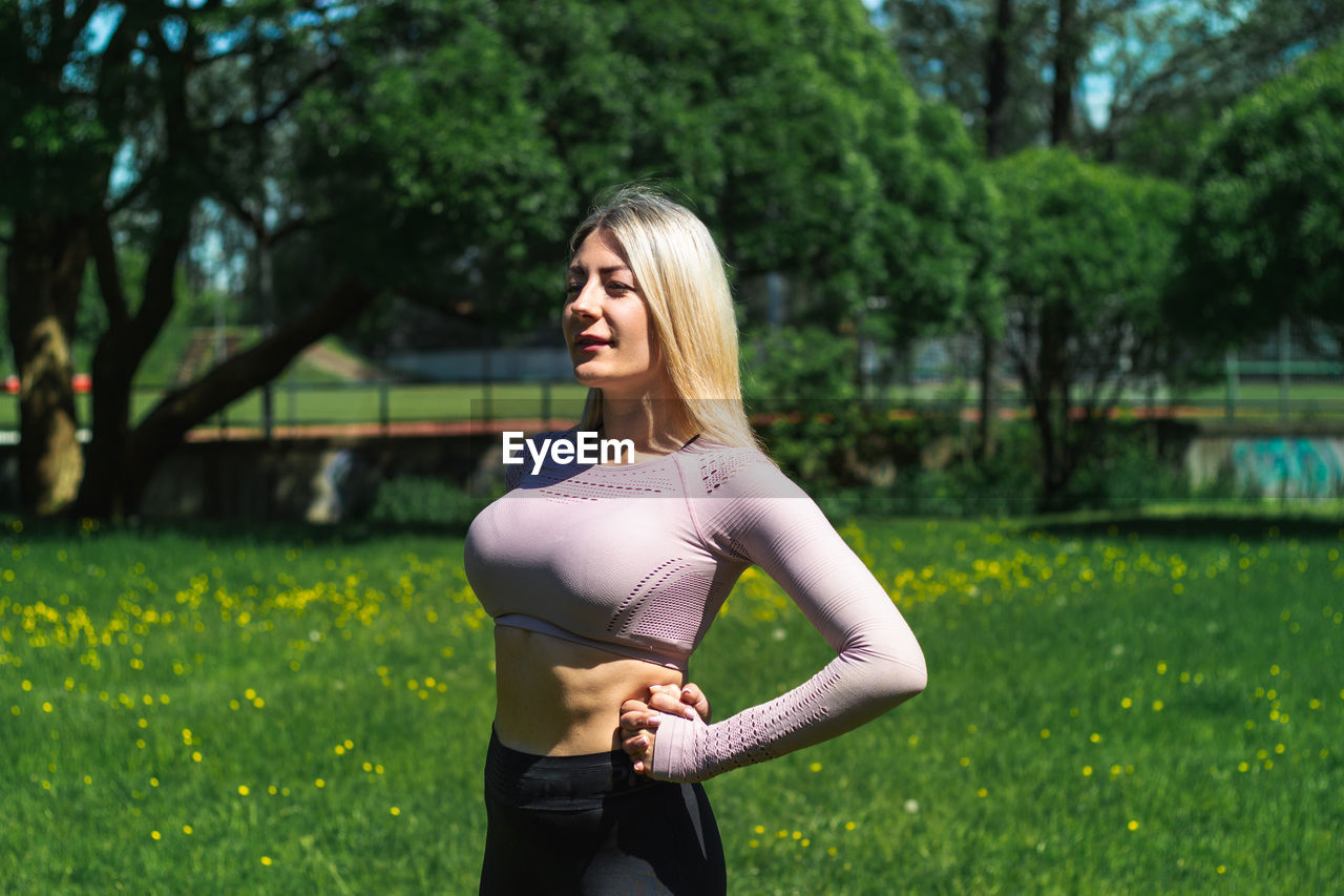 Young caucasian blond-haired woman in sportswear is doing yoga in the park. outdoor workout.