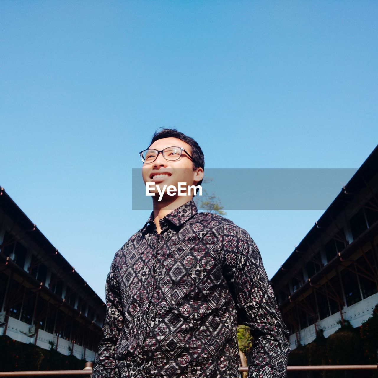 Low angle view of man looking away against clear blue sky