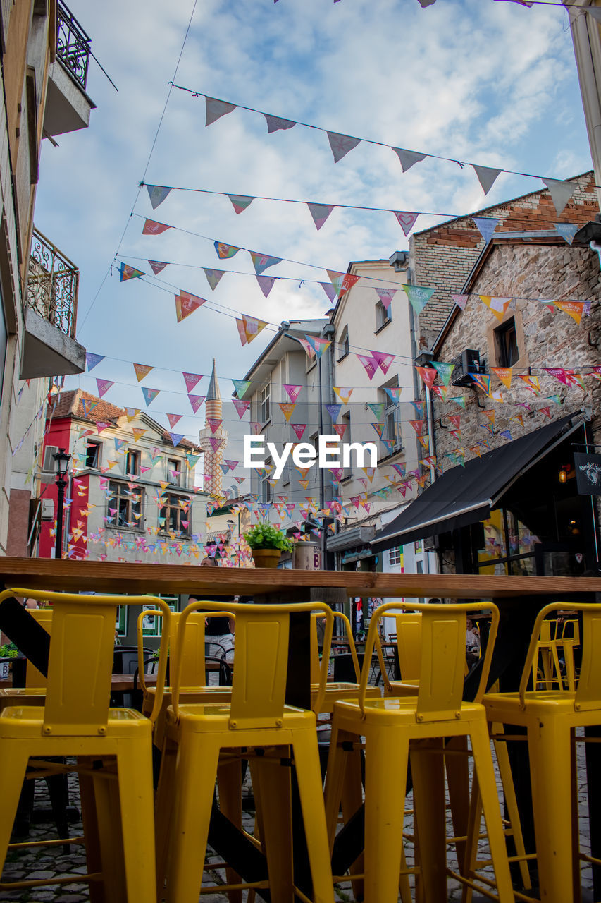 MULTI COLORED CHAIRS AND TABLE IN RESTAURANT AGAINST BUILDINGS