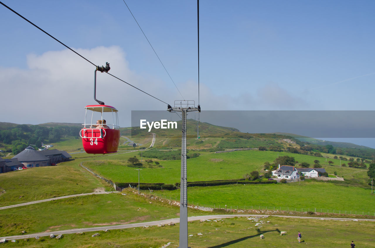 OVERHEAD CABLE CAR ON LAND AGAINST SKY