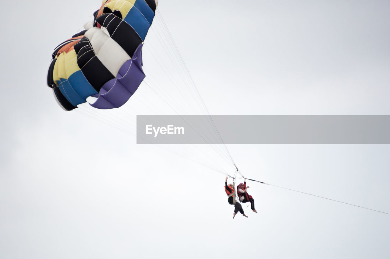 LOW ANGLE VIEW OF PEOPLE FLYING KITE