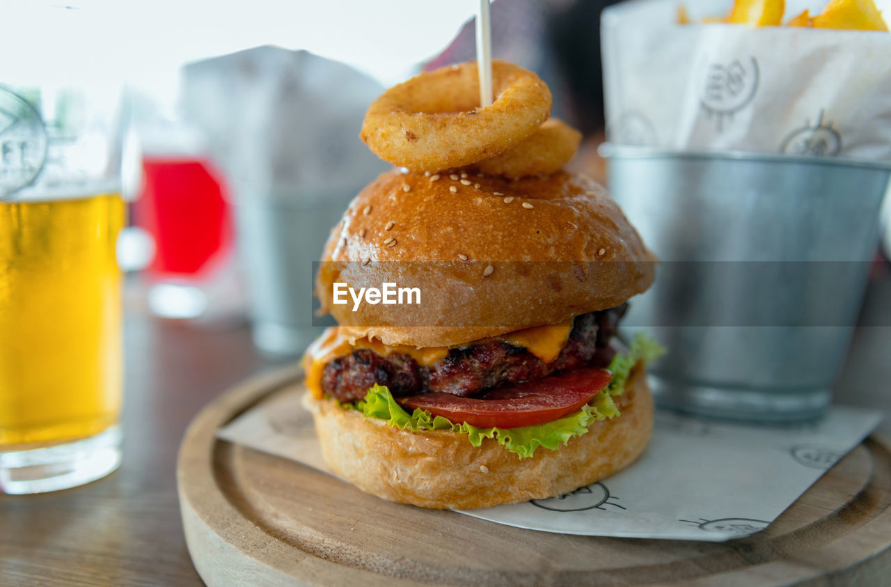 Delicious hamburger served on wooden board on table in pub