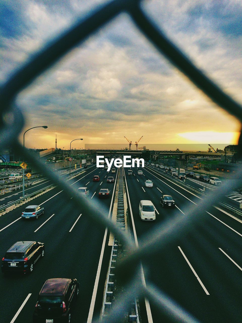 Cars on street seen through chainlink fence