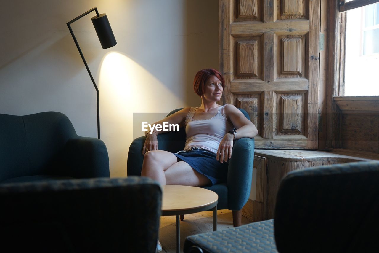 Smiling young woman sitting on armchair at home