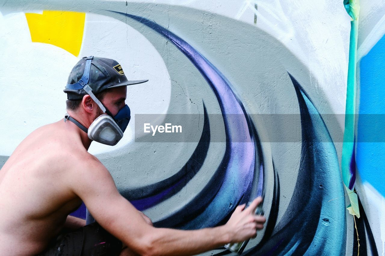 Side view of man spraying graffiti