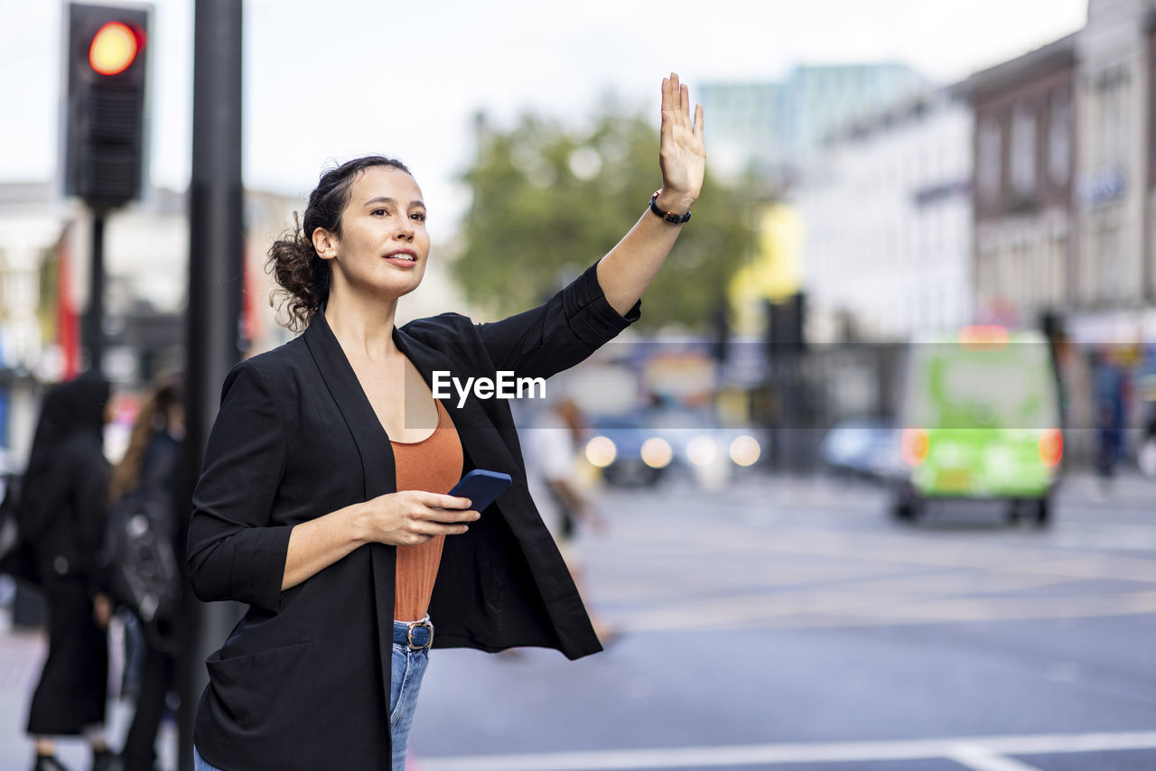 Businesswoman hailing ride on road in city