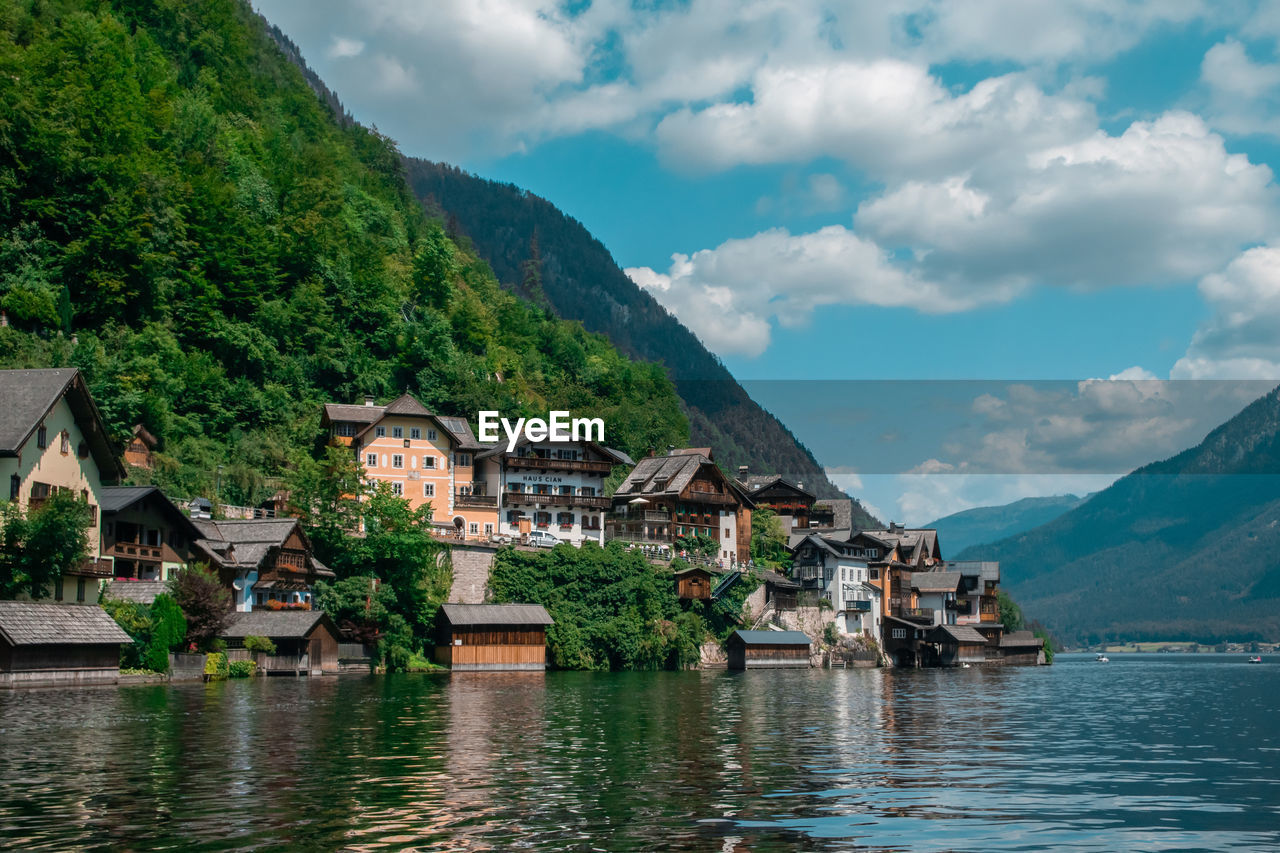 Houses by river and buildings against sky