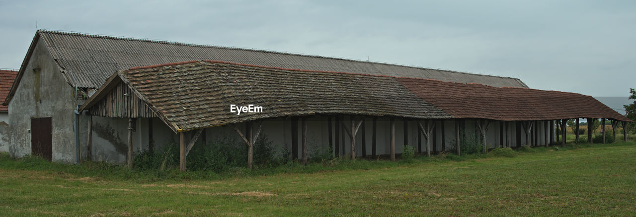 OLD BARN ON FIELD AGAINST BUILDINGS