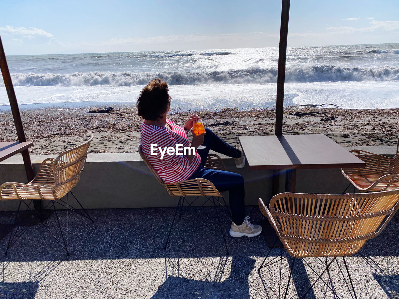 Rear view of woman sitting on chair at beach