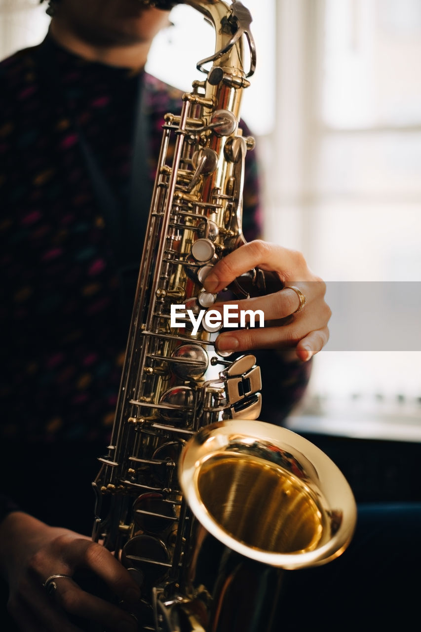 Midsection of woman playing saxophone at studio