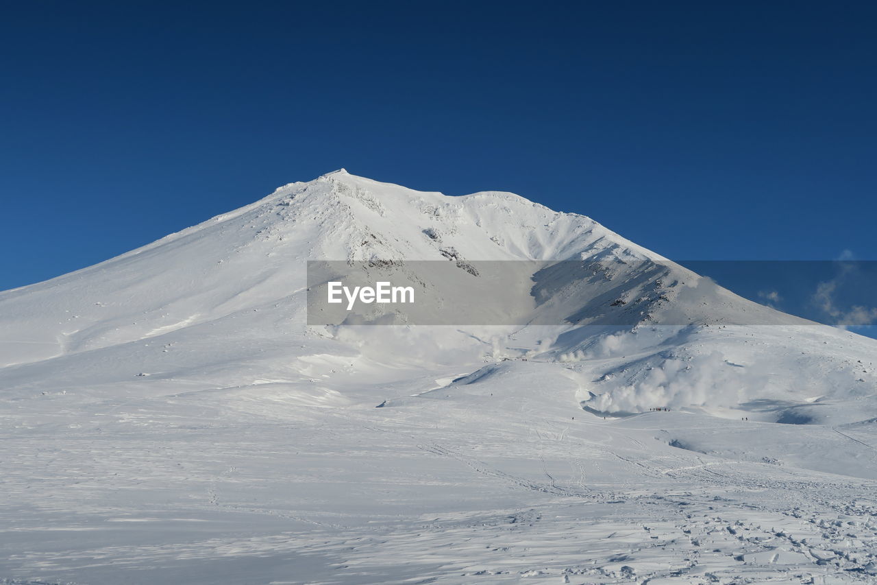 Scenic view of snowcapped mountains against clear blue sky