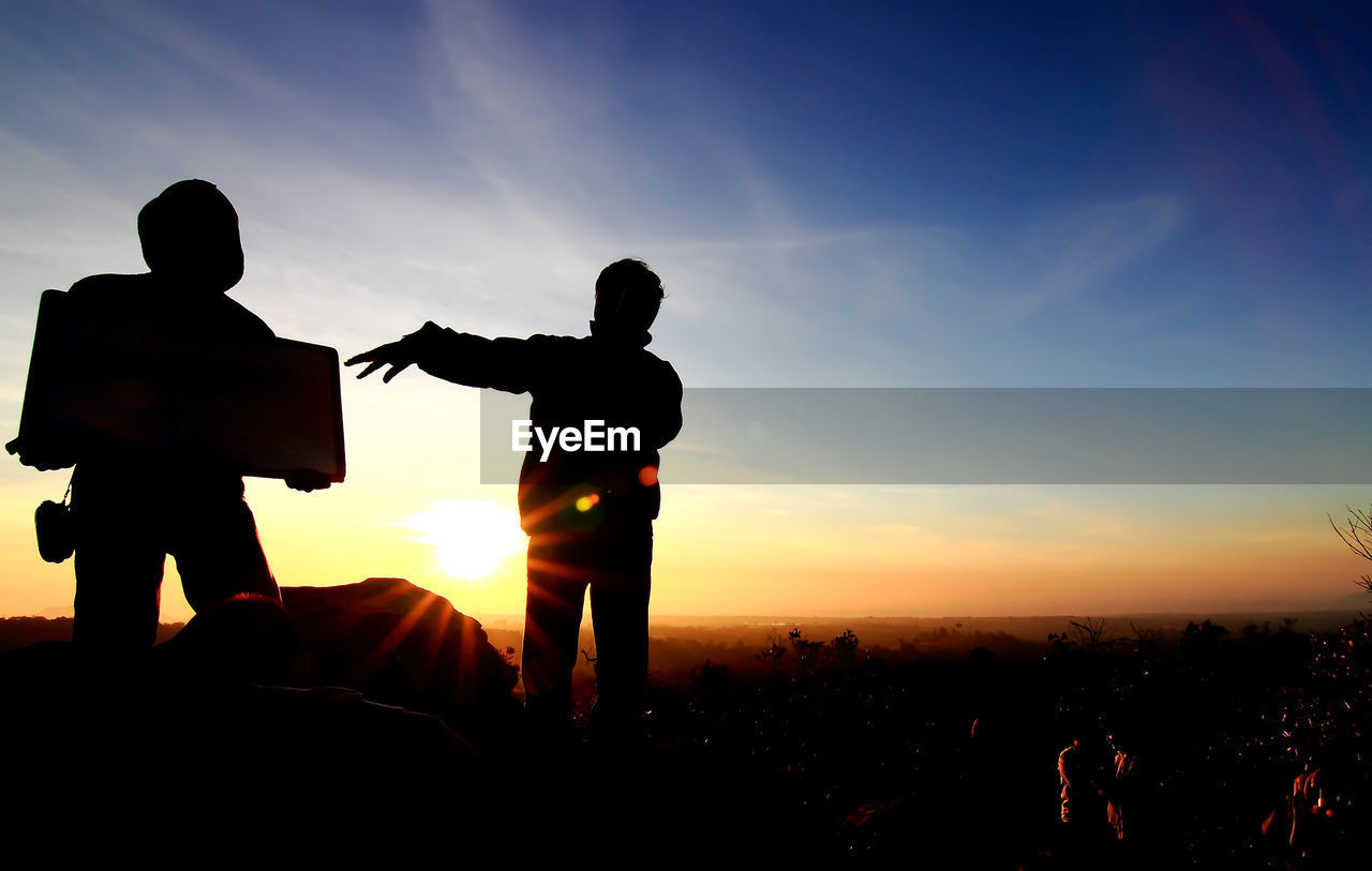 Silhouette people standing on field against sky during sunset