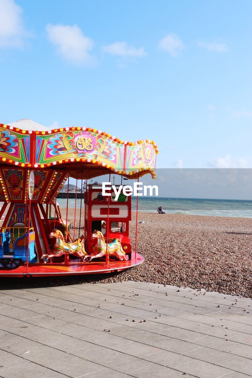 CAROUSEL AT BEACH AGAINST SKY