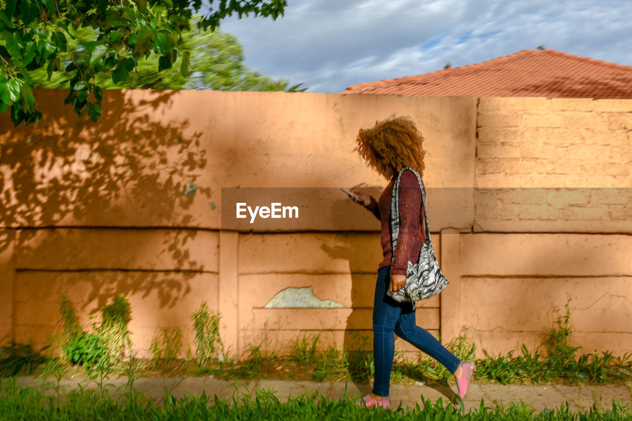 SIDE VIEW OF WOMAN WALKING BY BUILDING