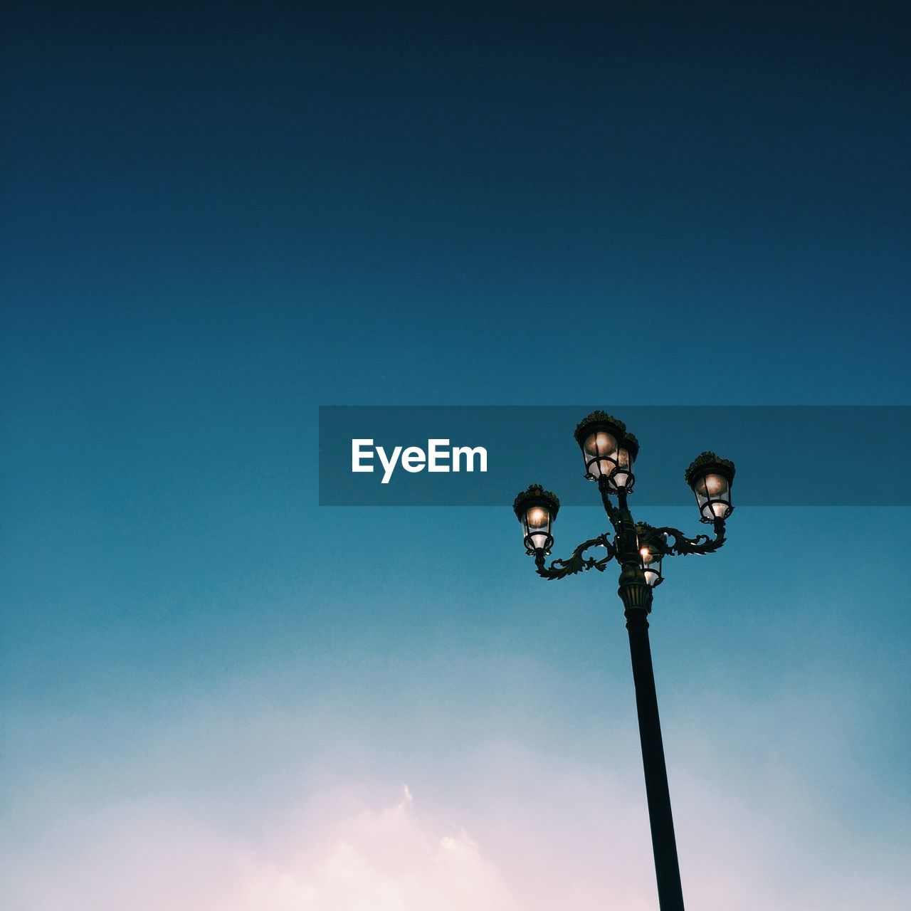 Low angle view of illuminated street light against clear blue sky