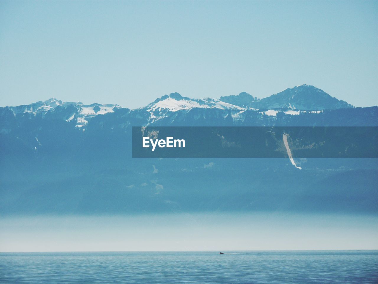 Scenic view of sea and mountains against clear sky