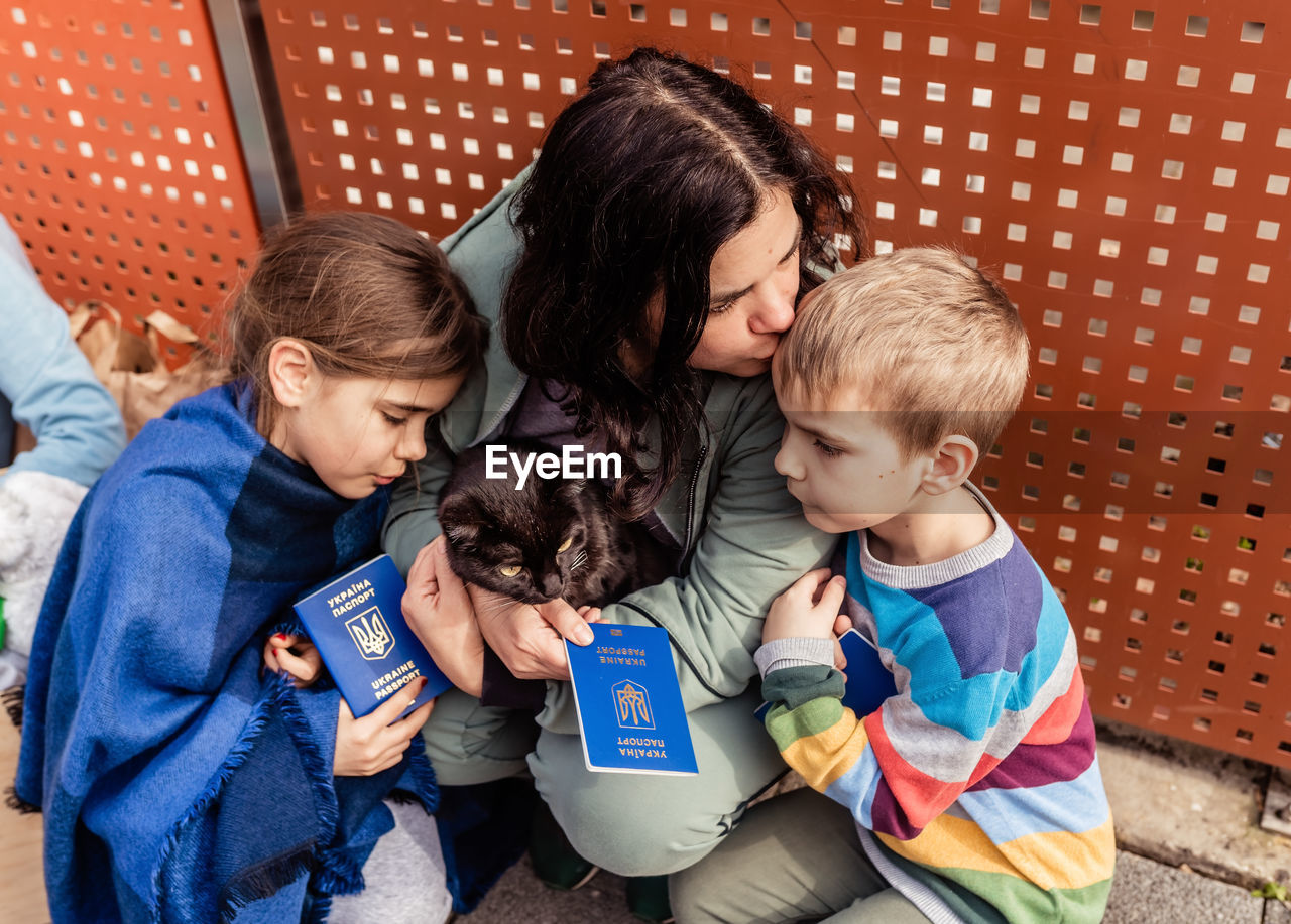 Mother with children and cat holding passports fleeing from ukraine waiting for help registration
