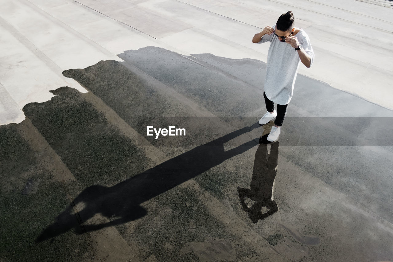 High angle view of man standing on puddle at street