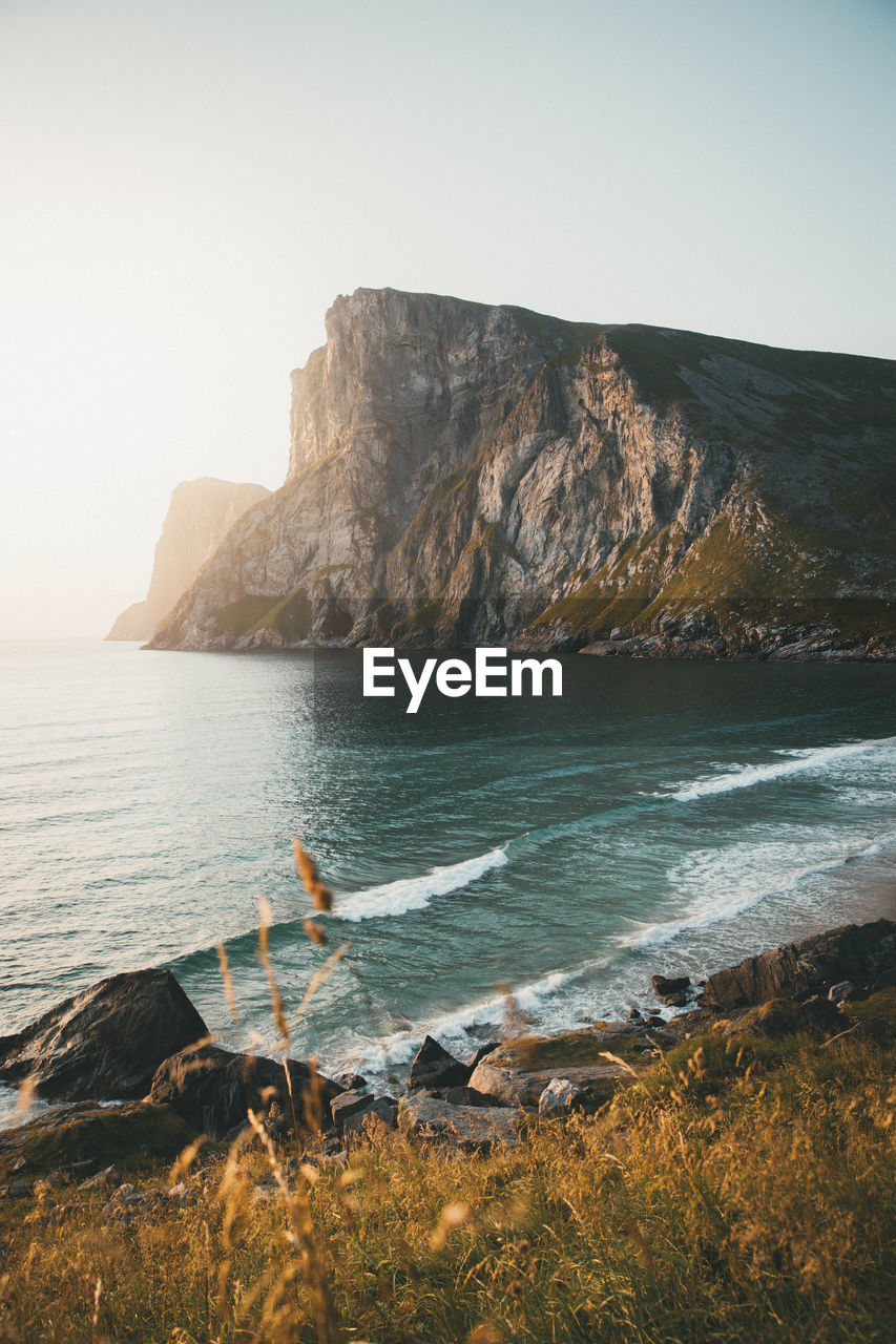 Rock formations by sea against clear sky