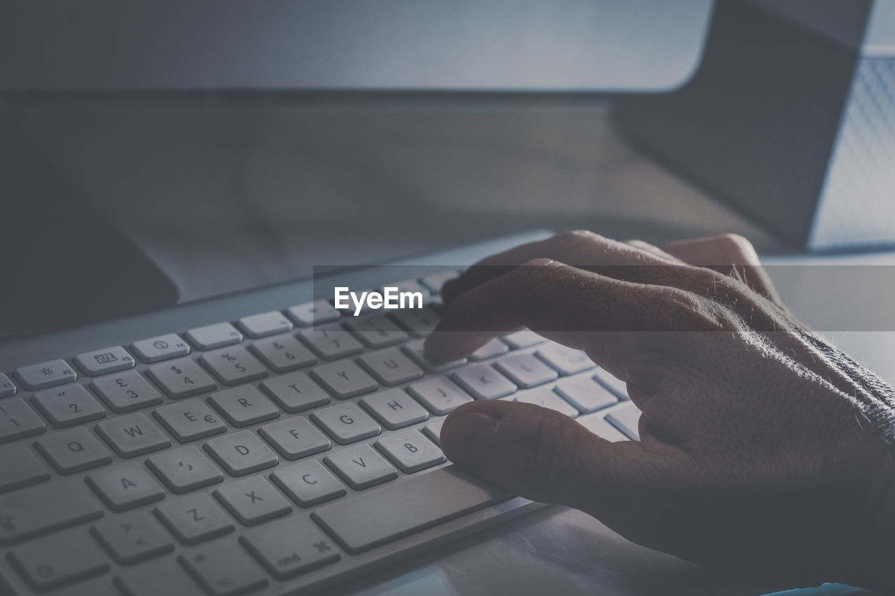 Hand typing on a modern design keyboard on the desk. view of fingers pressing the keys, soft focus