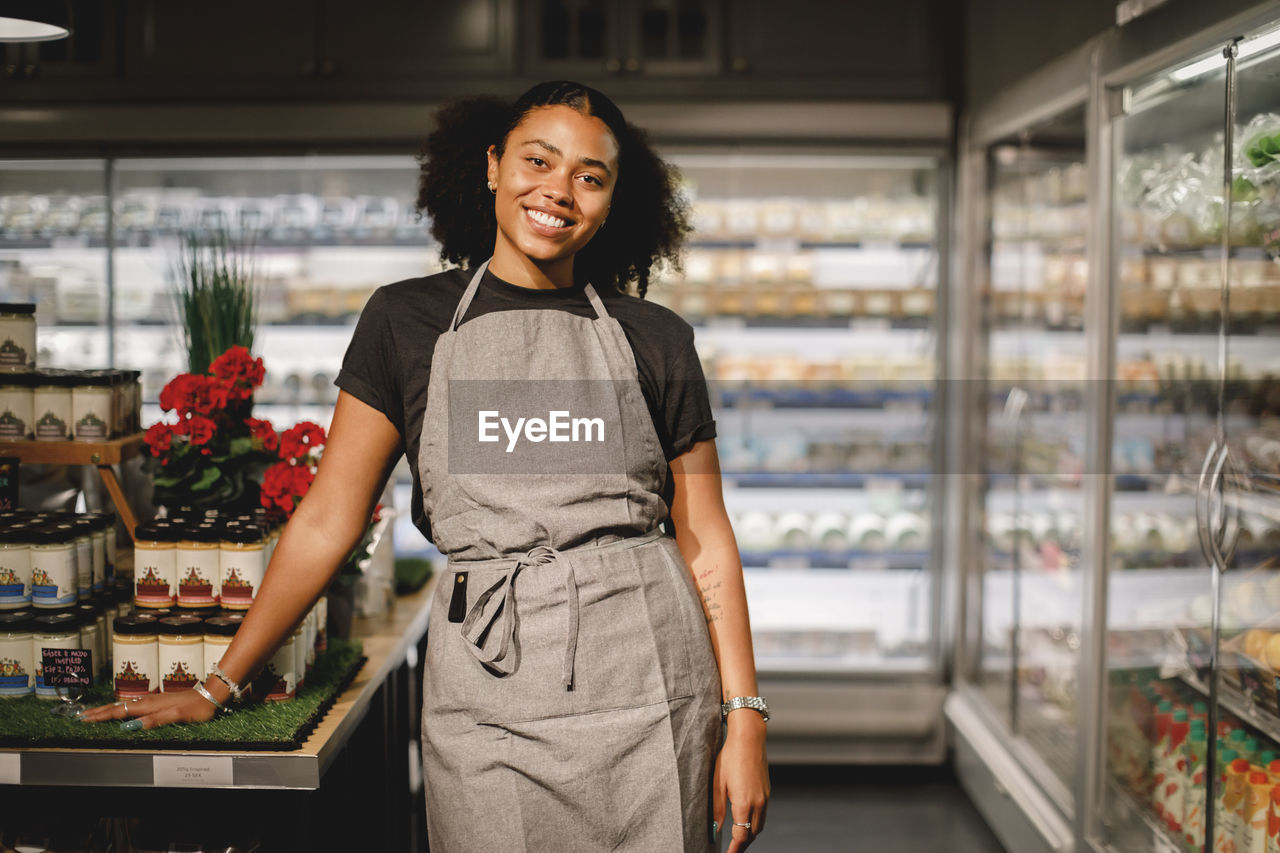 Portrait of smiling saleswoman standing in grocery store