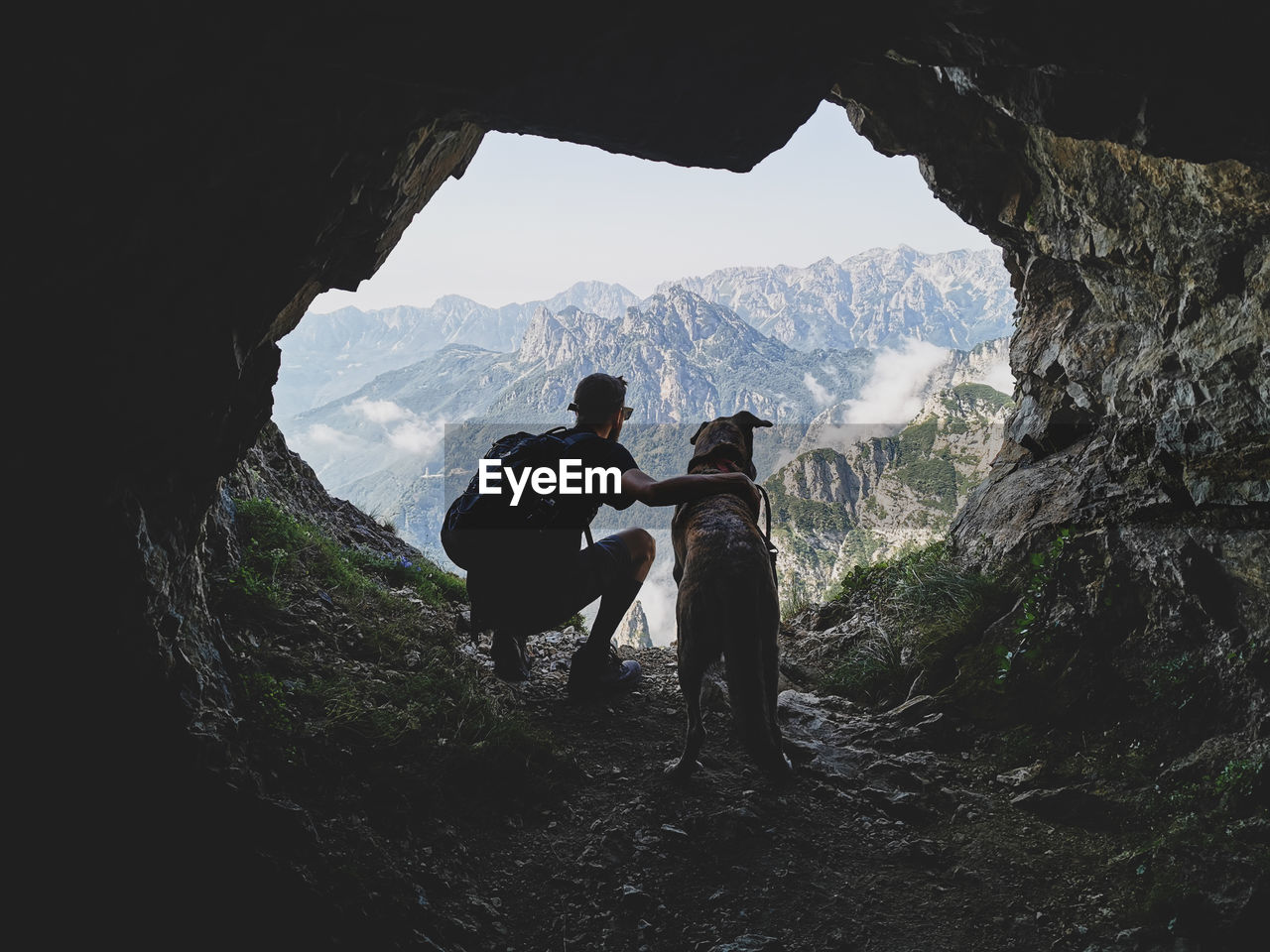 Men and dog on rock against mountains