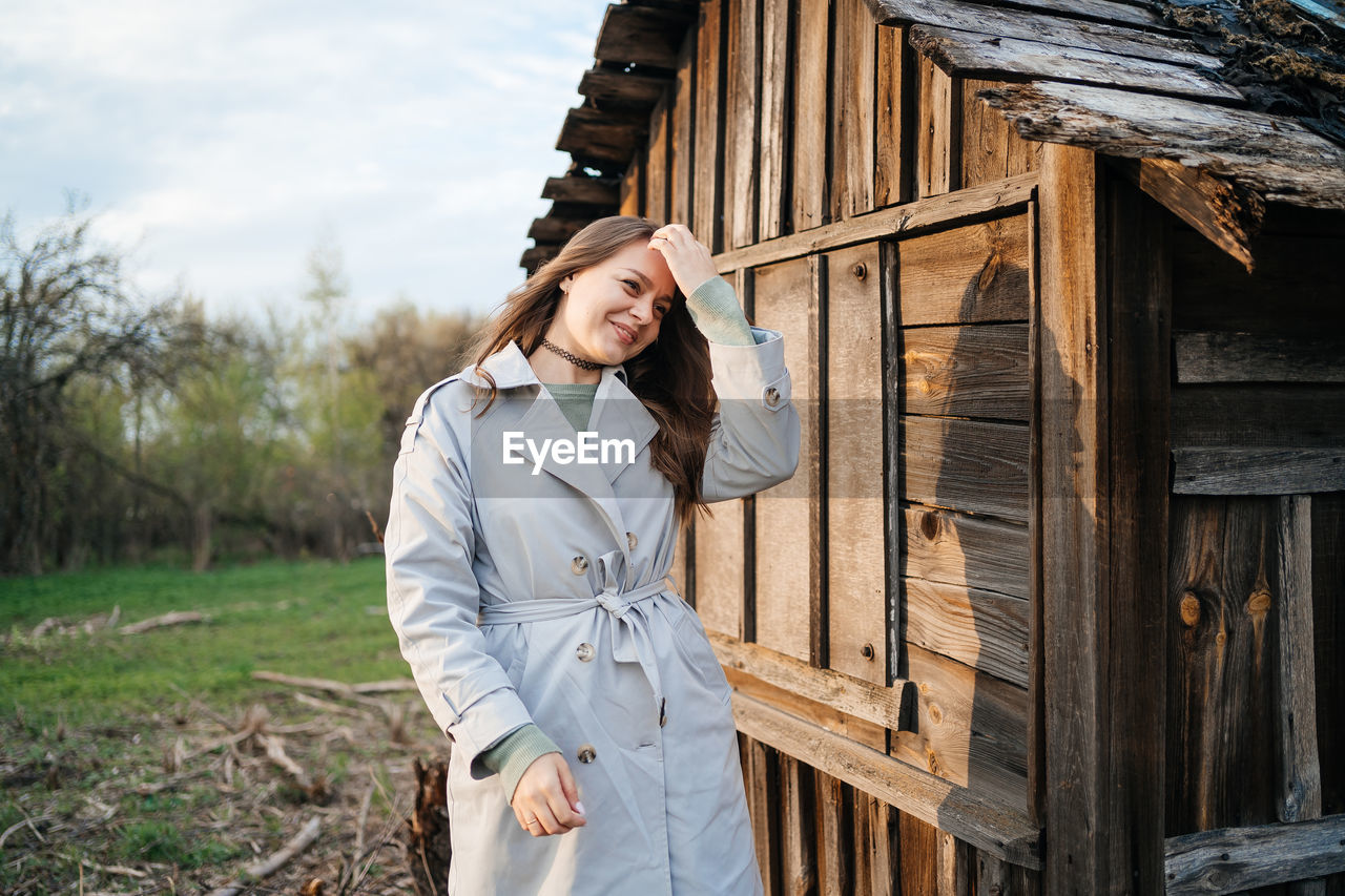 Girl with long hair in a grey trench coat outdoors in spring