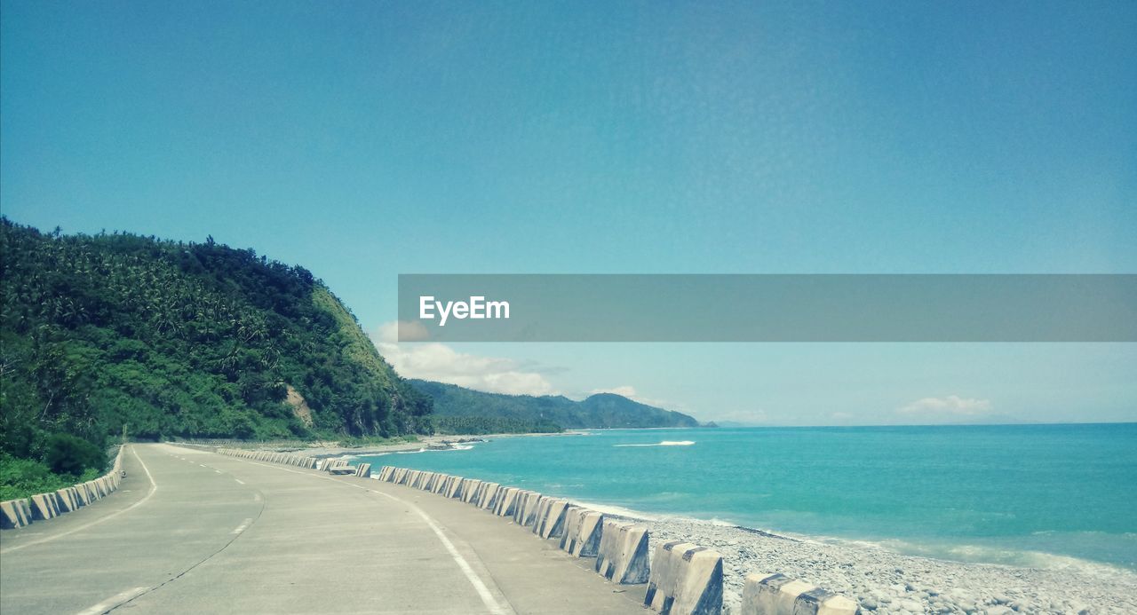 Scenic view of road by sea against sky