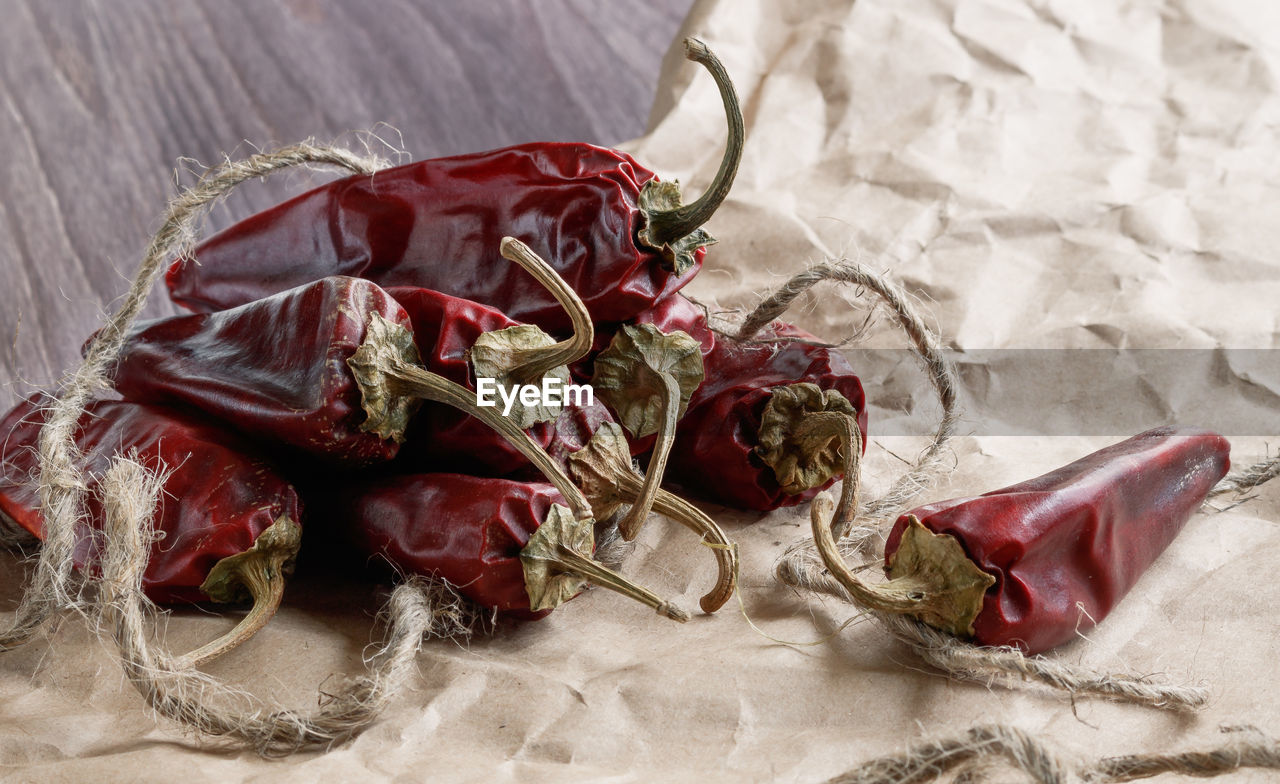 Close-up of dry red chili peppers with rope on paper bag at table