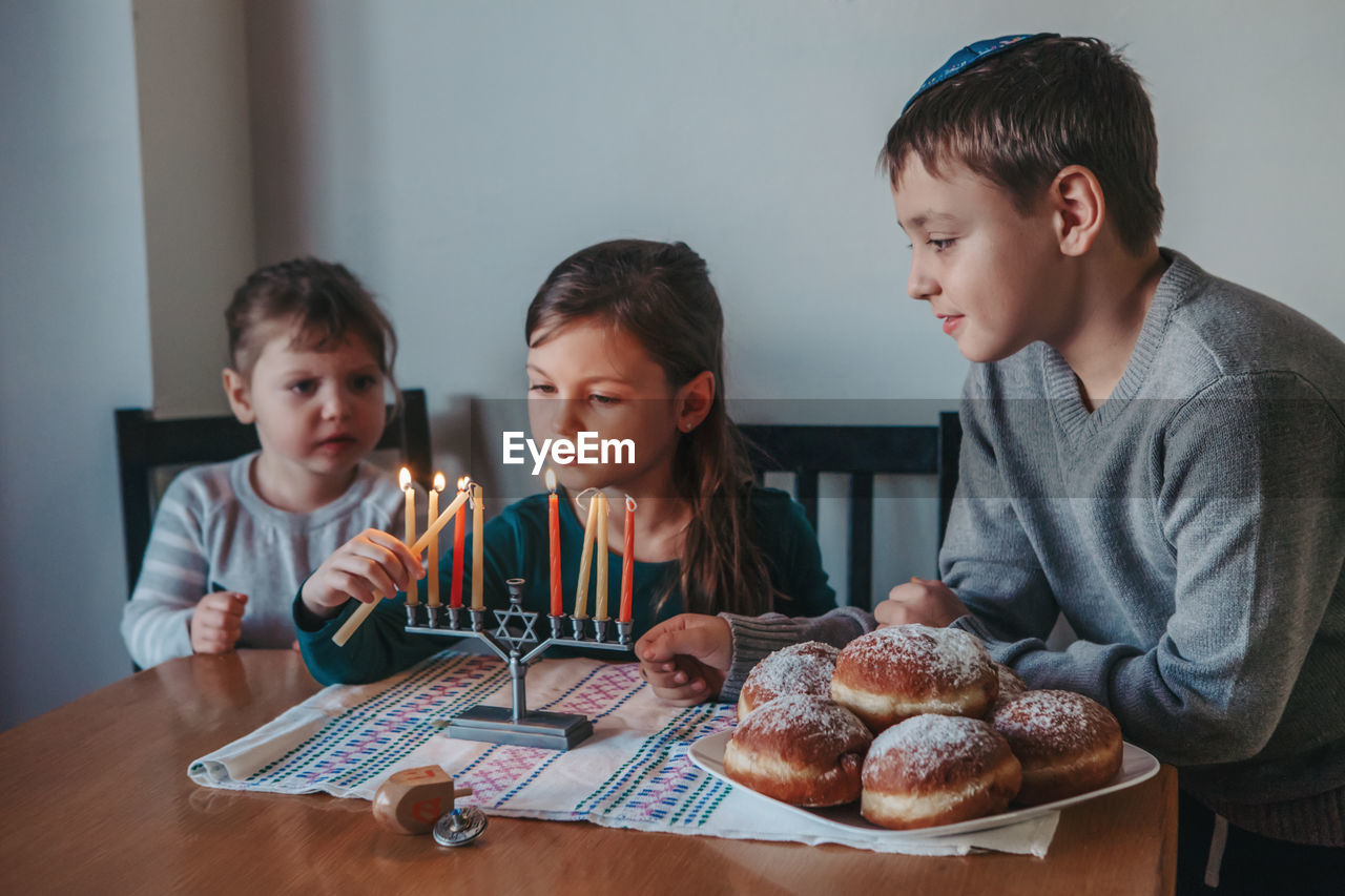 Cute kids igniting candles at home