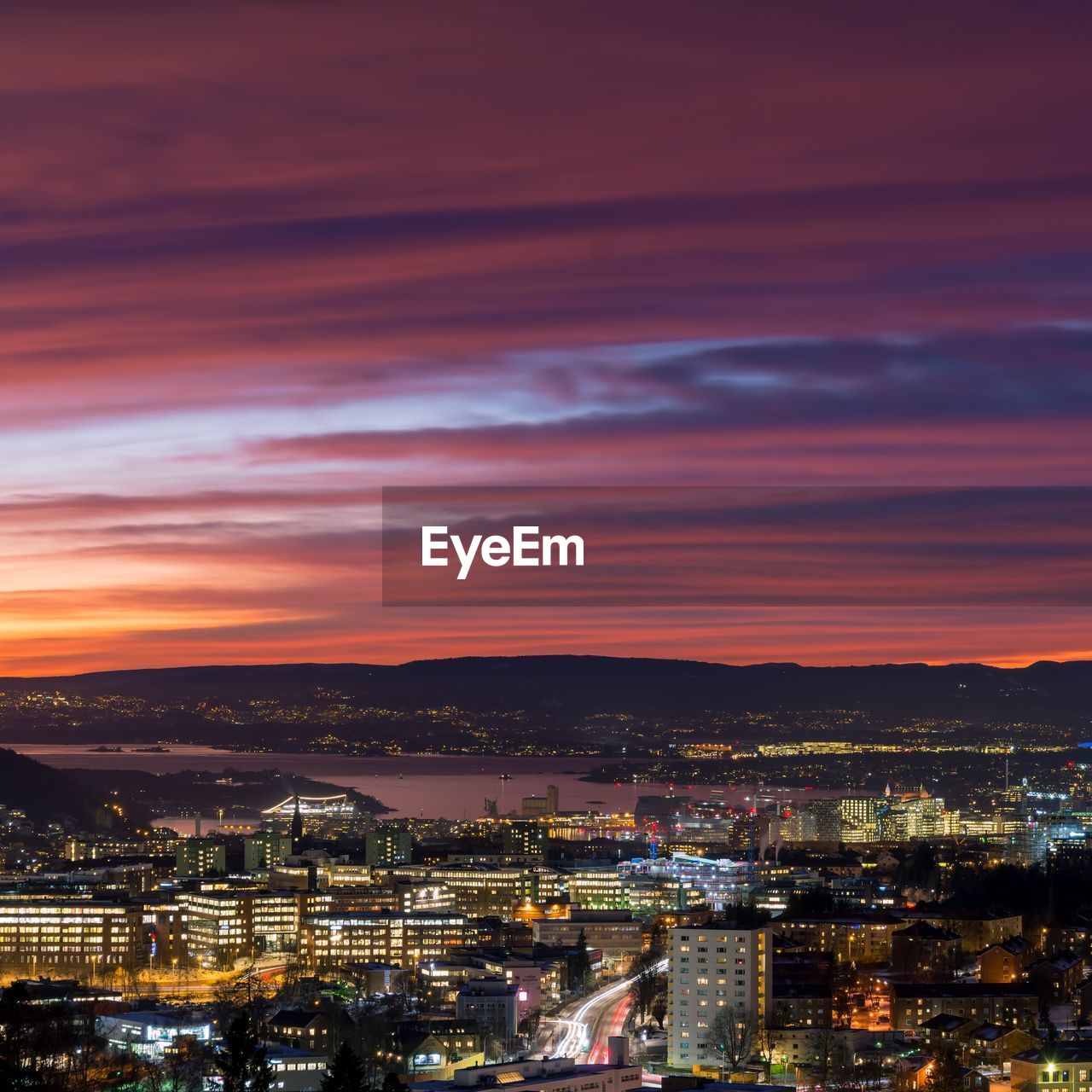 HIGH ANGLE VIEW OF ILLUMINATED CITY AT SUNSET