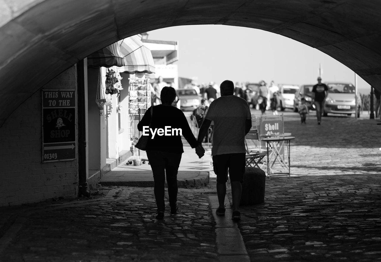 Rear view of couple walking under archway