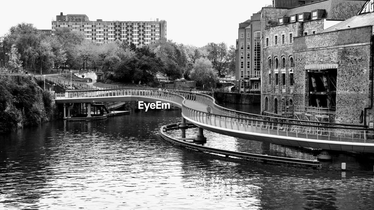 ARCH BRIDGE OVER RIVER AMIDST BUILDINGS IN CITY