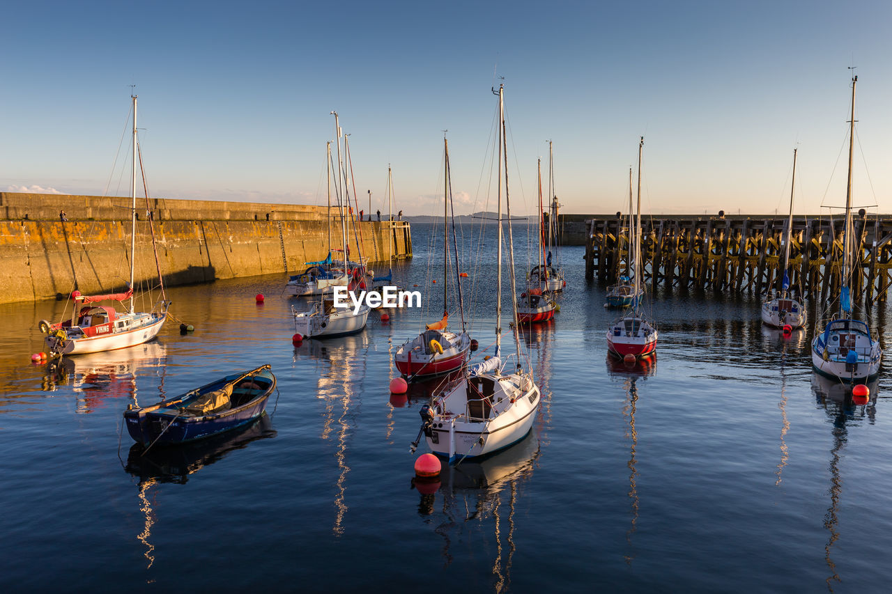 Sailboats moored in sea against clear sky