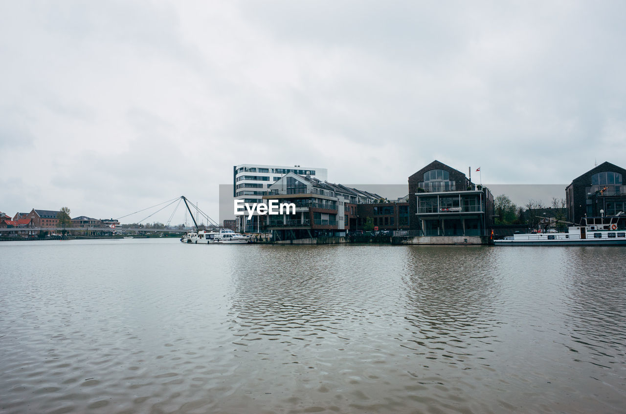 Lake by buildings against sky