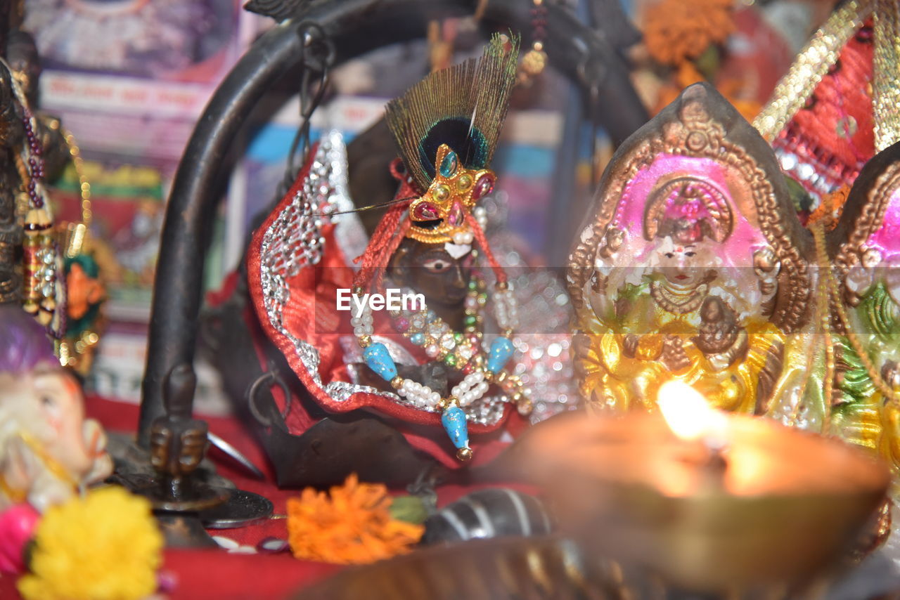 Close-up of lit diya and idol figurines in temple