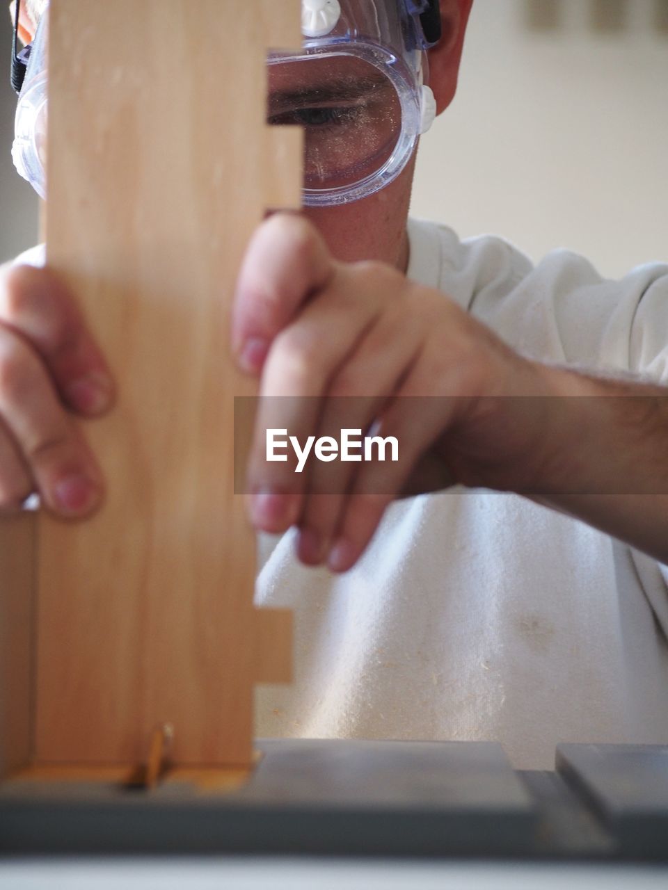 Close-up of carpenter working with wooden plank at desk