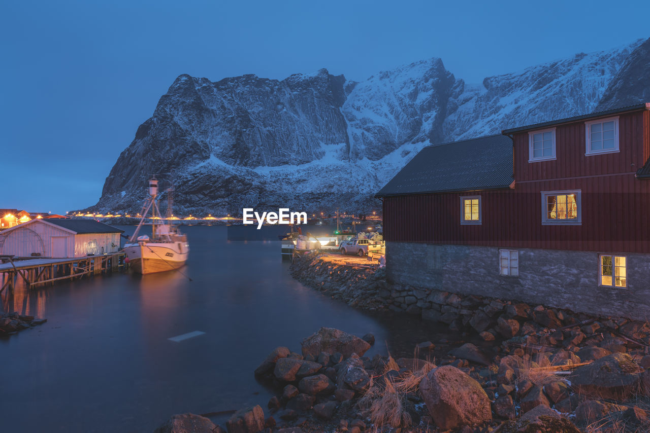 ILLUMINATED CITY BY MOUNTAIN AGAINST SKY AT NIGHT