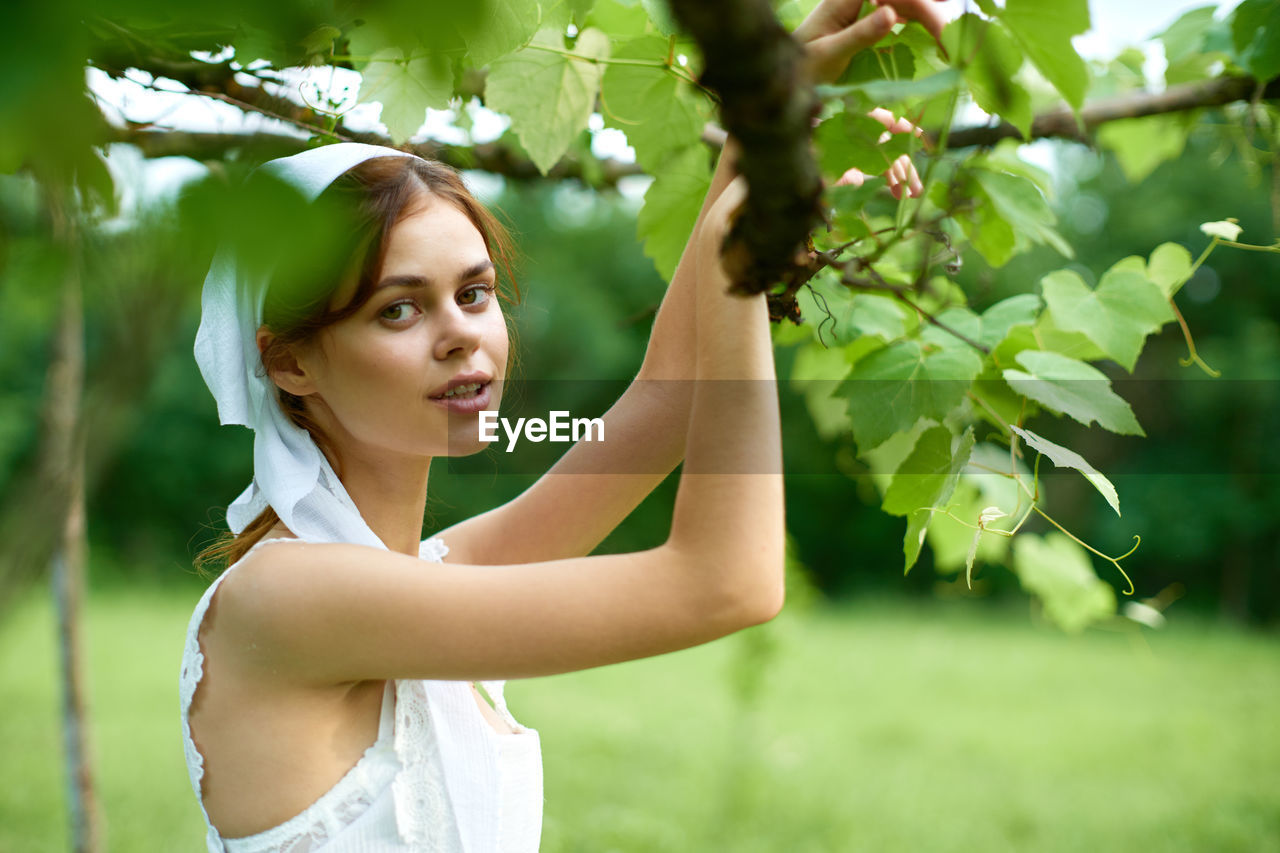 portrait of smiling young woman standing against plants